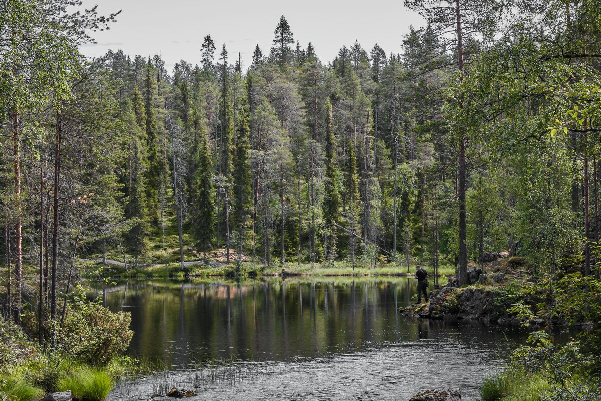 Retkeilijä tutkii karttaa erämaajärven rannalla auringonlaskussa